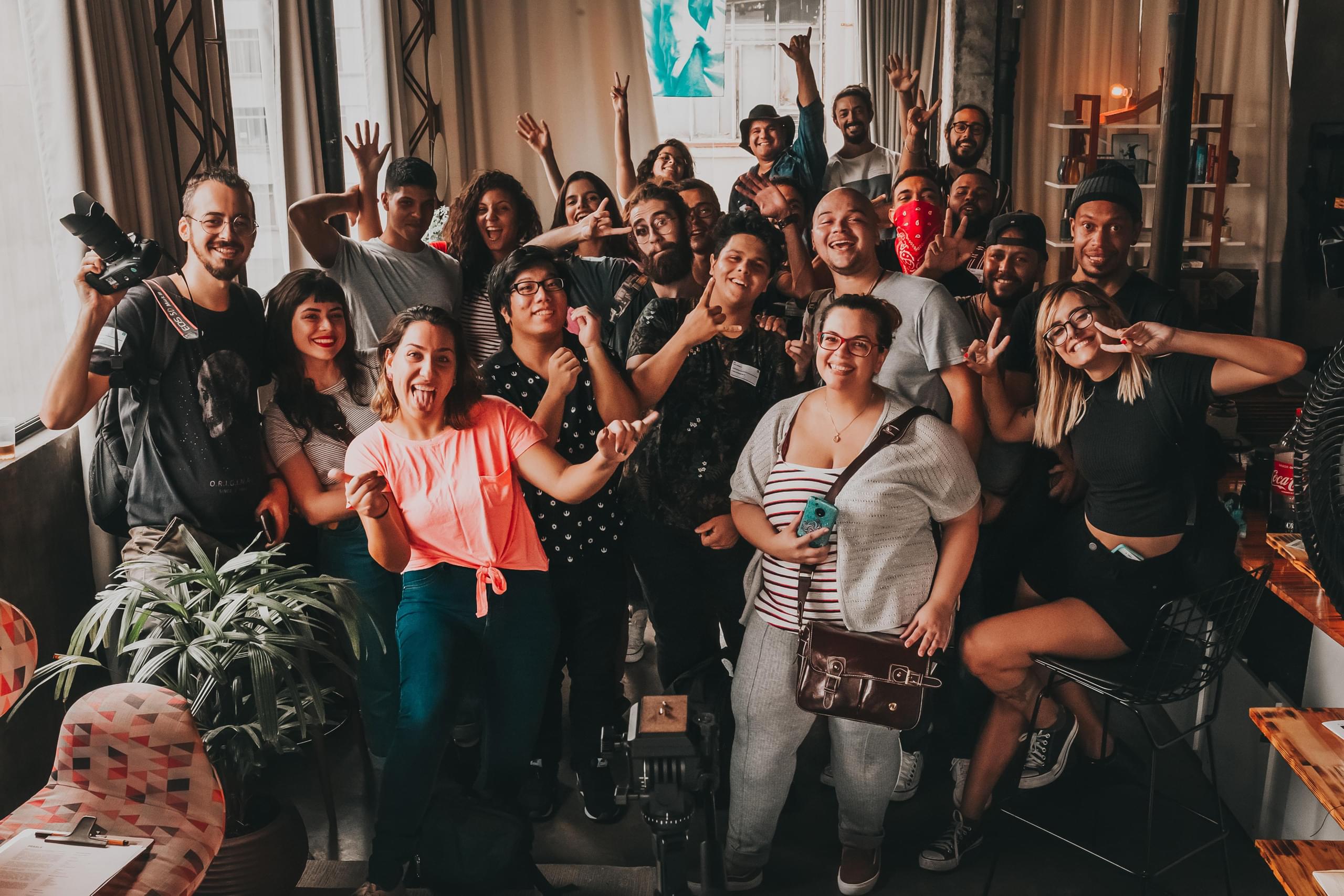 A group of people in a warm, wood-toned room. They're all posing for the camera and smiling.